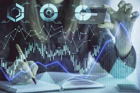 Double exposure of woman on-line shopping holding a credit card and financial graph drawing. Stock...