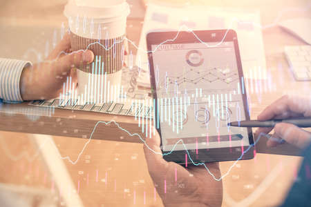 Double exposure of mans hands holding and using a phone and financial chart drawing. Market analysis...