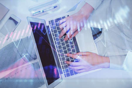 Double exposure of woman hands working on computer and forex graph hologram drawing. Top View....