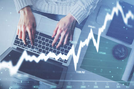 Multi exposure of woman hands working on computer and forex chart hologram drawing. Top View....