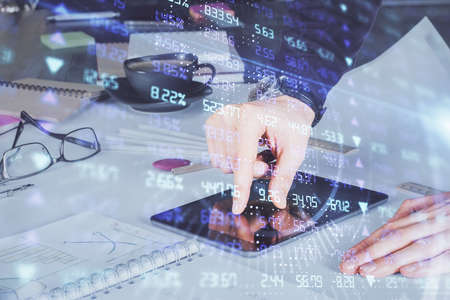 Double exposure of mans hands holding and using a digital device and forex graph drawing. Financial...