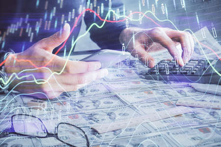 Double exposure of mans hands holding and using a digital device and forex graph drawing. Financial market concept.の写真素材