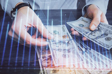 Multi exposure of financial graph drawing hologram and USA dollars bills and man hands. Analysis concept.の写真素材