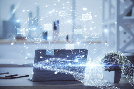 Desktop computer background in office and flying envelops hologram drawing. Double exposure. Electronic mail concept.の写真素材