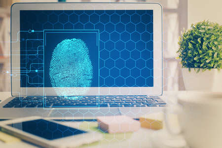 Computer on desktop in office with finger print drawing. Double exposure. Concept of business data security.の写真素材