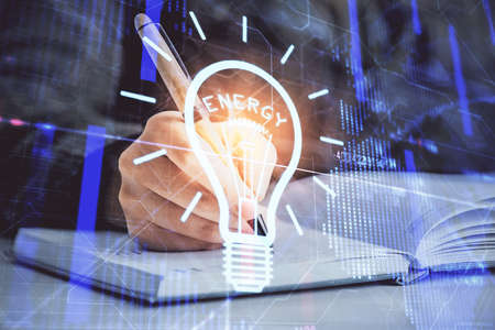 Bulb hologram over hands taking notes background. Concept of idea. Double exposureの写真素材
