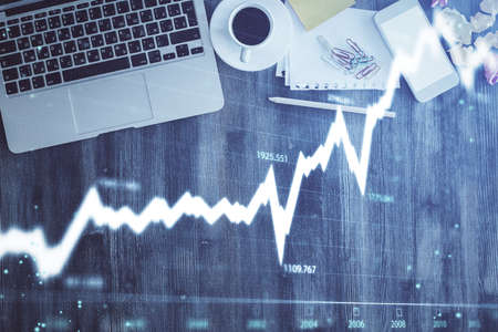 Financial market graph and top view computer on the desktop background. Double exposure. Investment...
