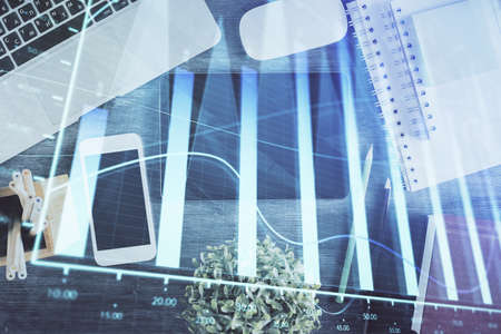 Double exposure of forex chart hologram over desktop with phone. Top view. Mobile trade platform...