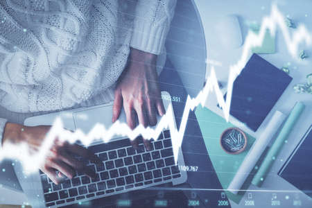 Multi exposure of woman hands working on computer and forex chart hologram drawing. Top View....