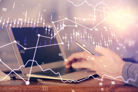 Double exposure of mans hands holding and using a digital device and forex graph drawing. Financial...