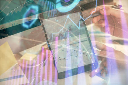 Double exposure of mans hands holding and using a phone and financial chart drawing. Market analysis...