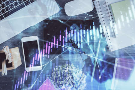 Double exposure of forex chart hologram over desktop with phone. Top view. Mobile trade platform...