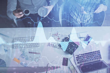 Double exposure of man and woman working together and financial chart hologram drawing. market...