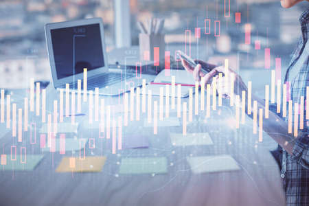 Double exposure of woman hands working on computer and forex graph hologram drawing. Financial...
