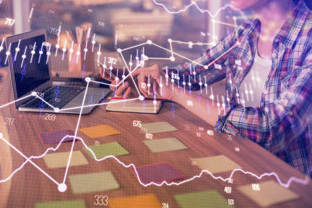 Double exposure of businesswoman hands typing on computer and forex graph hologram drawing....