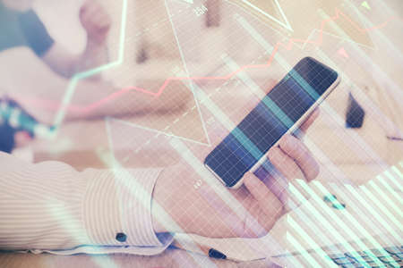 Double exposure of mans hands holding and using a digital device and forex graph drawing. Financial market concept.の写真素材