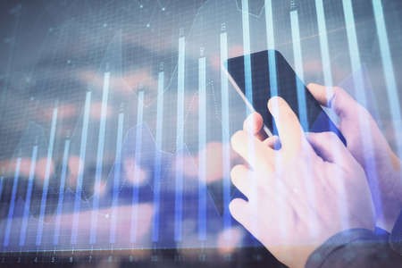 Double exposure of mans hands holding and using a digital device and forex graph drawing. Financial market concept.の写真素材