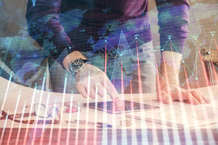 Double exposure of mans hands holding and using a digital device and forex graph drawing. Financial...