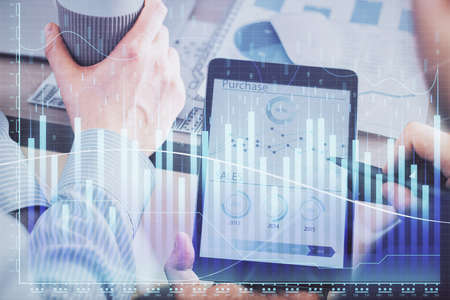 Double exposure of mans hands holding and using a phone and financial chart drawing. Market analysis...