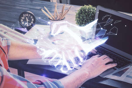 Handshake hologram drawing with businessman working on computer on background. Double exposure.の写真素材