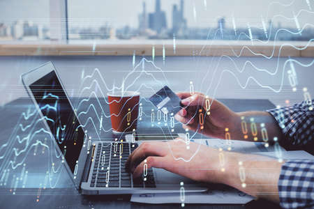 Double exposure of man hands holding a credit card and Forex graph drawing. Stock trading and...