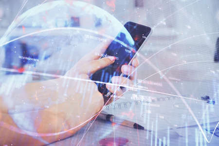 Double exposure of mans hands holding and using a digital device and forex graph drawing. Financial...