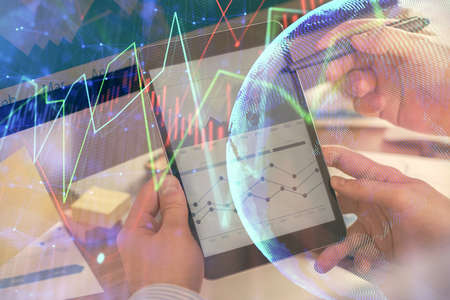 Double exposure of mans hands holding and using a phone and financial chart drawing. Market analysis...