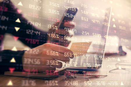 Double exposure of mans hands holding and using a phone and financial graph drawing. Analysis...
