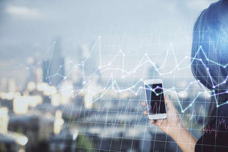 Double exposure of forex chart sketch hologram and woman holding and using a mobile device. Stock market concept.の写真素材