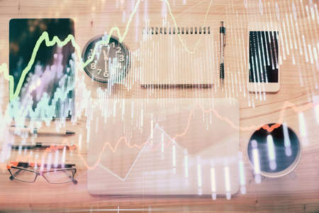 Double exposure of forex graph hologram over desktop with phone. Top view. Mobile trade platform...