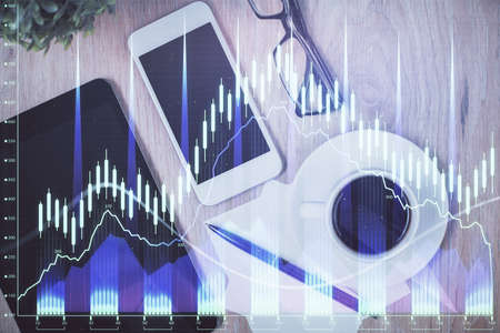 Double exposure of forex chart hologram over desktop with phone. Top view. Mobile trade platform...