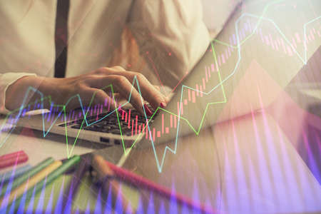 Double exposure of woman hands typing on computer and financial graph hologram drawing. Stock market...