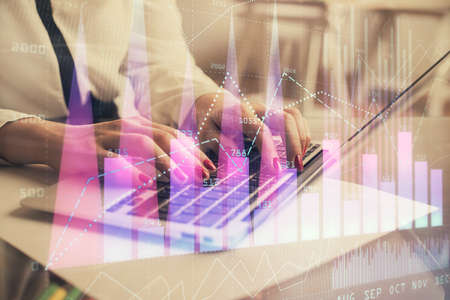 Multi exposure of woman hands typing on computer and financial graph hologram drawing. Stock market...