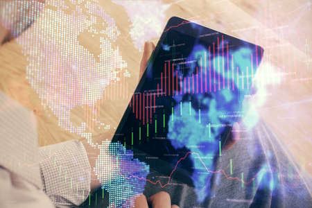Double exposure of mans hands holding and using a digital device and forex graph drawing. Financial...