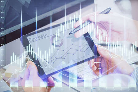 Double exposure of mans hands holding and using a phone and financial chart drawing. Market analysis...