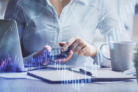 Double exposure of forex chart sketch hologram and woman holding and using a mobile device....