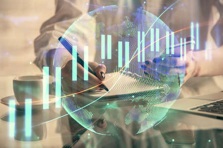 Double exposure of financial graph sketch hologram and woman holding and using a mobile device....