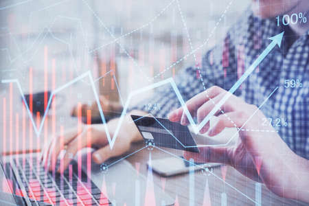 Double exposure of man hands holding a credit card and Forex graph drawing. Stock trading and digital fintech in Internet E-commerce concept.の写真素材