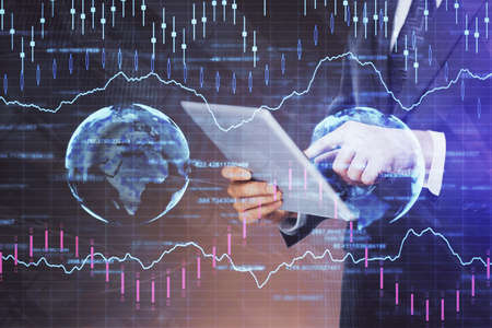 Double exposure of mans hands holding and using a digital device and forex graph drawing. Financial...