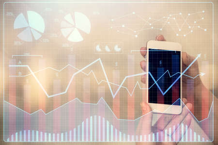 Double exposure of forex graph sketch hologram and woman holding and using a mobile device. Stock...