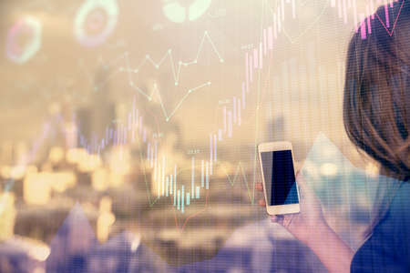 Double exposure of forex chart sketch hologram and woman holding and using a mobile device. Stock...