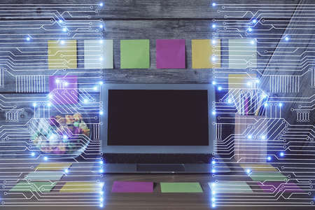 Computer on desktop in office with technology theme hologram. Double exposure. Tech concept.