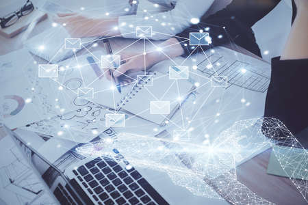 E-mail envelop theme hologram over hands taking notes background. Concept of electronic mail. Double...