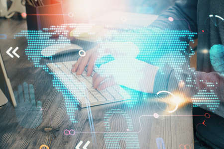 Double exposure of world map hologram with man working on computer on background. Concept of...