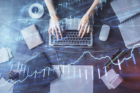 Multi exposure of woman hands working on computer and forex chart hologram drawing. Top View....