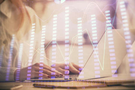 Double exposure of woman hands working on computer and forex graph hologram drawing. Financial...