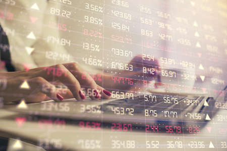 Multi exposure of woman hands typing on computer and financial graph hologram drawing. Stock market...