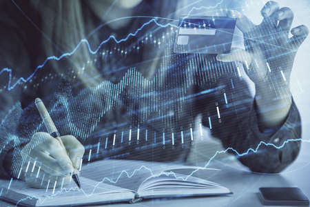 Double exposure of woman on-line shopping holding a credit card and financial graph drawing. Stock market E-commerce concept.の写真素材