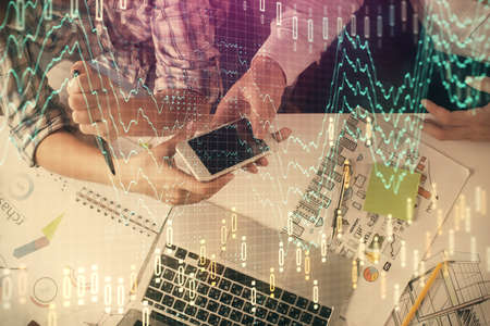 Double exposure of forex graph drawing and man and woman working together holding and using a mobile...