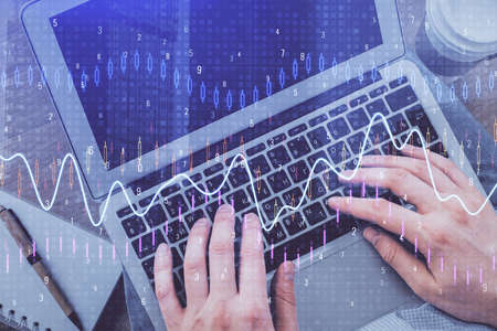 Double exposure of mans hands typing over computer keyboard and forex graph hologram drawing. Top view. Financial markets concept.の写真素材